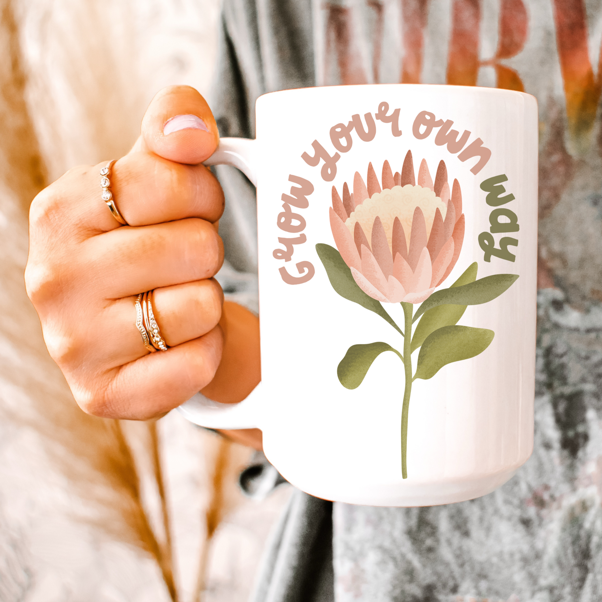 Frau mit Tasse in der Hand - Tasse mit Protea Blume und dem Schriftzug Grow your own way