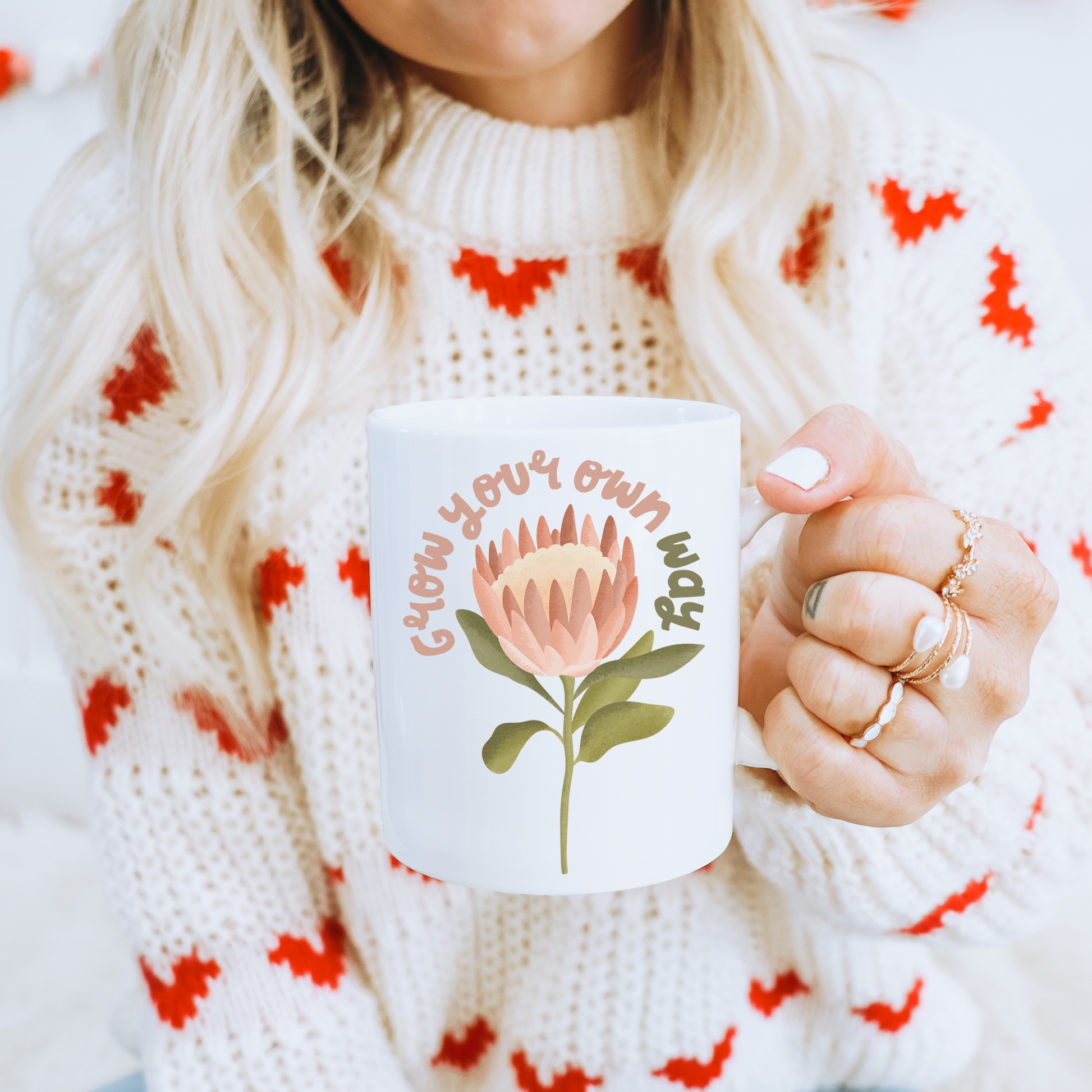 Frau mit Tasse in der Hand - Tasse mit Protea Blume und dem Schriftzug Grow your own way