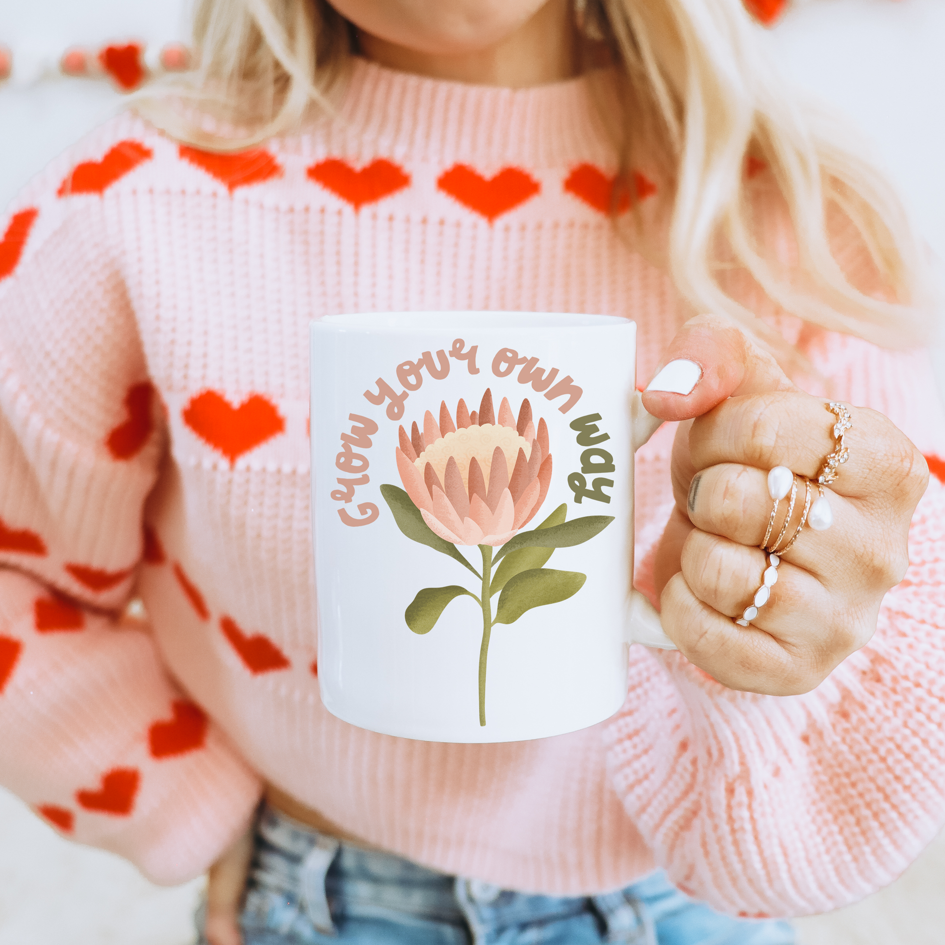 Frau mit Tasse in der Hand - Tasse mit Protea Blume und dem Schriftzug Grow your own way